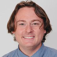 Scottie smiling with a gray background and wearing a rainbow tie
